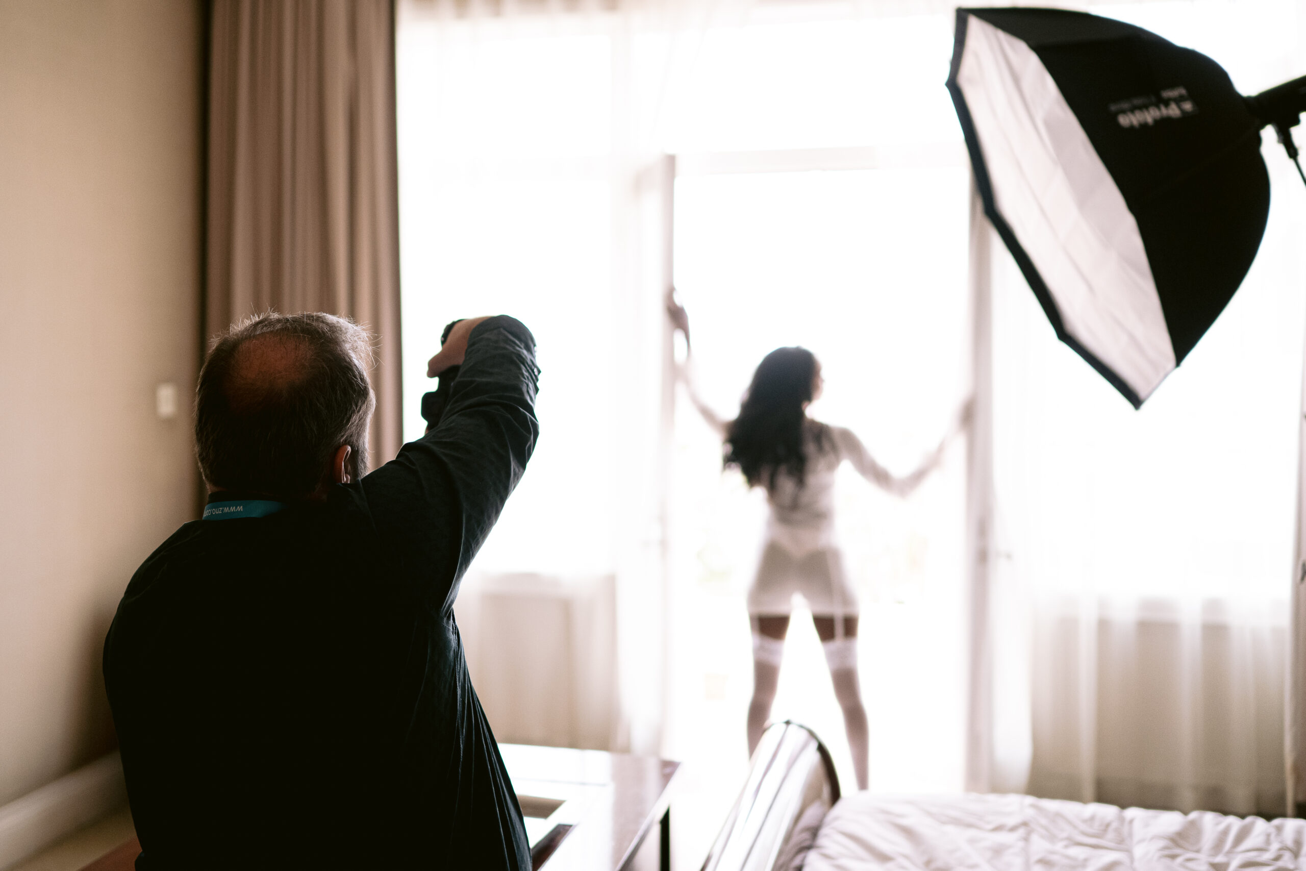 Photographer shooting a boudoir session by a bright window